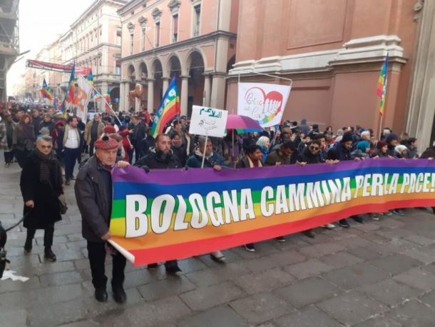 persone in marcia con le prime che tengono in mano uno striscione arcobaleno inneggiante la pace