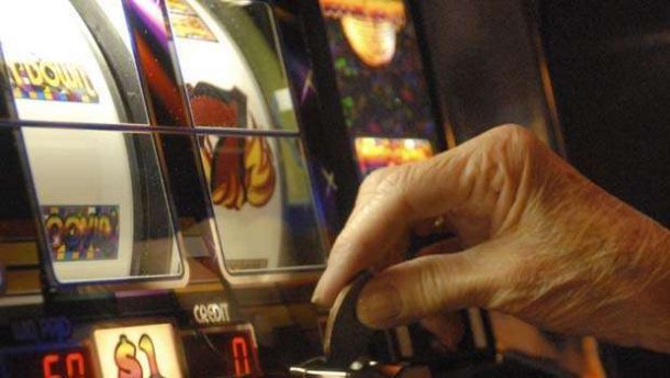 una mano intenta a giocare dei soldi all'interno di una slot machine